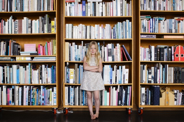 Girl (6-7) standing in front of bookshelf