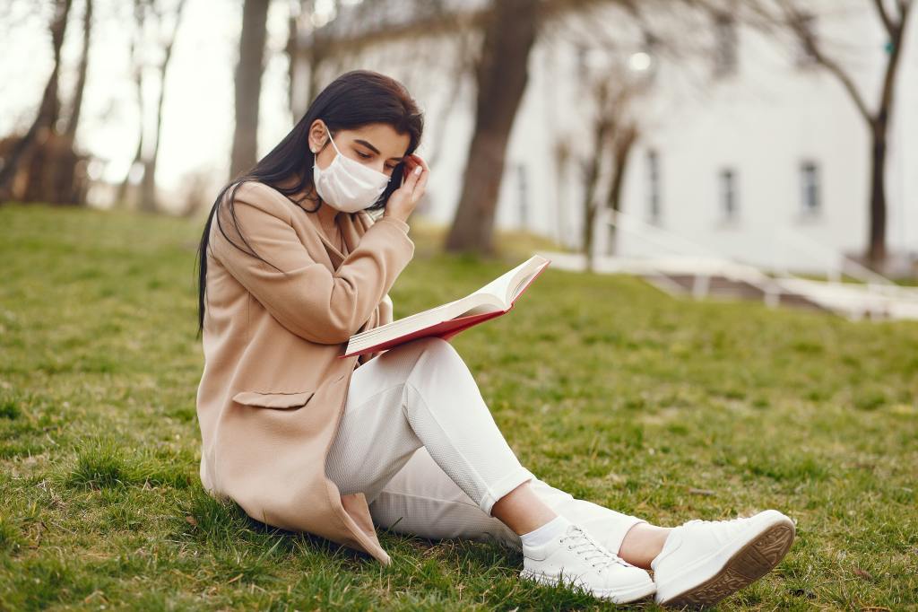 charming-woman-reading-book-on-lawn-in-square